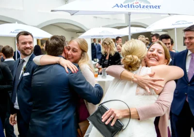Gäste umarmen sich bei einer Hochzeit auf Schloss Hohenkammer, festgehalten vom Hochzeitsfotografen bei der Trauung.
