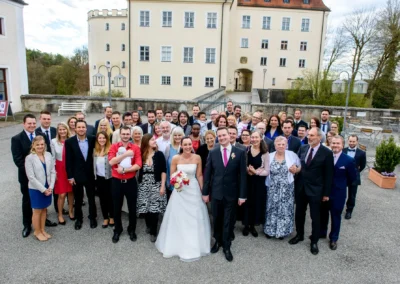 Hochzeitsgesellschaft vor Schloss Seefeld versammelt, Brautpaar mittig, festliche Kleidung, Hochzeitsreportage.