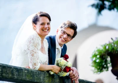 Brautpaar lacht auf einer Trauung im Schloss Amerang, Hochzeitsreportage mit Blumenstrauss und eleganter Garderobe.
