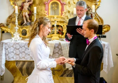 Brautpaar tauscht Ringe waehrend der Trauung im Schloss Aufhausen, zelebrierte Hochzeitsmomente, emotionale Zeremonie.