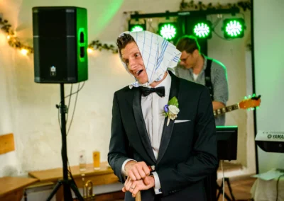 Bräutigam in Anzug mit Tuch auf dem Kopf bei Hochzeit in Schloss Pertenstein. Hochzeitsreportage in festlicher Stimmung.