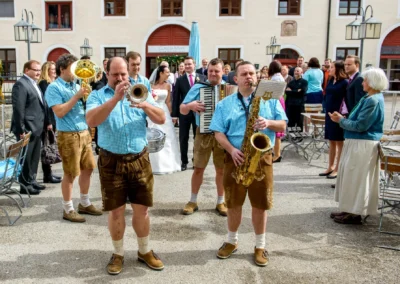 Blaskapelle bei Hochzeit im Schloss Seefeld, nahe Pilsensee, begleitet Trauung mit Musik in traditioneller Tracht.