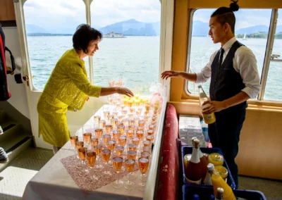Hochzeitsfeier im Hotel Aiterbach am Chiemsee mit Empfangsgetraenken auf einem Boot bei sonnigem Wetter.