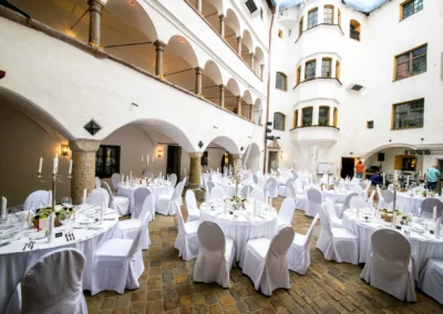 Hochzeitsfeier im Schloss Amerang mit festlich gedeckten Tischen im Innenhof, Aufnahme einer Hochzeitsreportage.