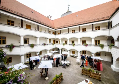 Hochzeitsgesellschaft im Innenhof von Schloss Hohenkammer; elegante Kulisse fuer Trauung und Hochzeitsreportage.