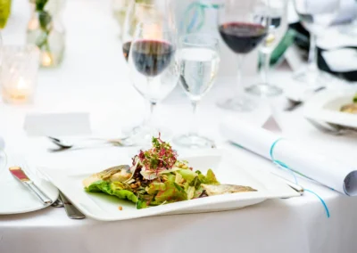 Hochzeitsessen mit Fisch und Salat bei Feier am Starnberger See. Elegante Tischdekoration mit Kerzen und Wein.