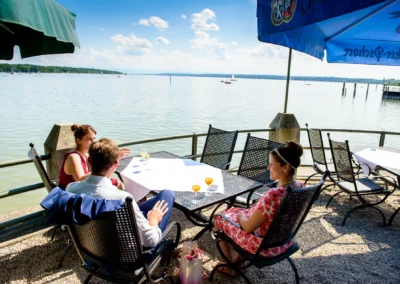 Gaste bei einer Hochzeitsfeier am Ammersee geniessen den Ausblick bei sonnigem Wetter im Seehaus Schreyegg.