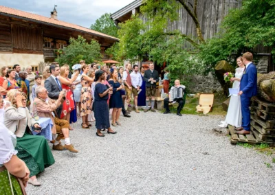 Hochzeitsfeier im Hasenoehrlhof in Geitau bei Bayrischzell mit Brautpaar und Gaesten in traditioneller Kleidung.