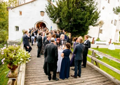 Gaste versammeln sich zur Hochzeit auf einer Holzbrucke bei Schloss Amerang. Elegante Trauung im Freien.