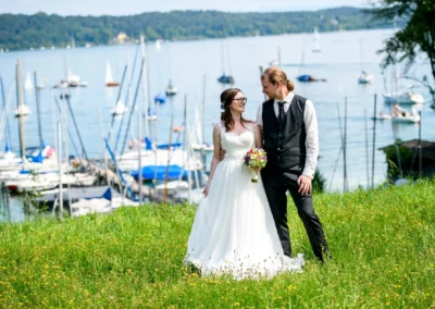 Brautpaar auf der Roseninsel am Starnberger See, umgeben von Sommerflora und Segelbooten im Hintergrund, Hochzeitsreportage.