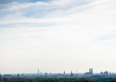 Blick auf München während Hochzeitsfeier, rote Luftballons steigen auf. Foto von Hochzeitsreportage in Bogenhausen.