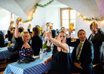 Hochzeitsfeier mit Gaesten, die bei Schloss Pertenstein anstossen und feiern, festliche Stimmung im Chiemgau.