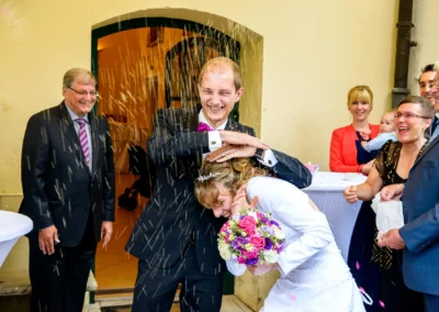 Brautpaar lacht unter Konfettiregen bei Hochzeit in Schloss Aufhausen, gefeiert in Aufhausen nahe Erding.