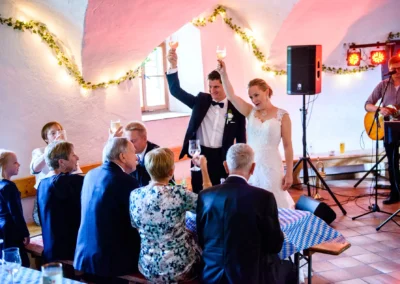 Brautpaar beim Anstoßen mit Hochzeitsgesellschaft im festlichen Saal bei Schloss Pertenstein, Traunreut.