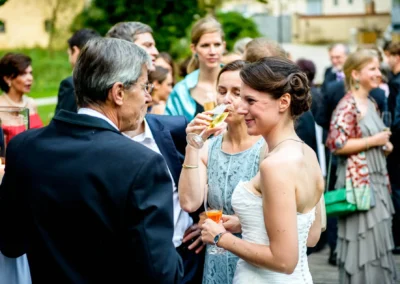 Gespraech bei Hochzeitsempfang im Schloss Amerang, Braut im Kreis von Gaesten, festliche Stimmung, Hochzeitsreportage.