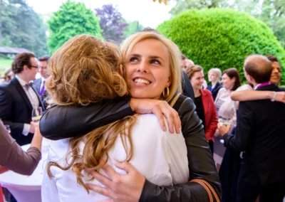 Gäste umarmen sich bei Hochzeit in Schloss Aufhausen, fröhliche Atmosphäre, Hochzeitsreportage.