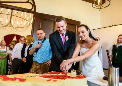 Brautpaar beim Anschneiden der Hochzeitstorte im Schloss Seefeld, Feststimmung bei der Hochzeitsfeier.