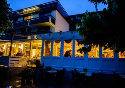 Nachtaufnahme einer Hochzeit im Seehotel Leoni bei Starnberg, beleuchteter Festsaal und Gaeste.
