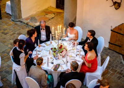 Gaste bei einer Hochzeit im Schloss Amerang, sitzend an festlich gedecktem Tisch, Teil einer Hochzeitsreportage.
