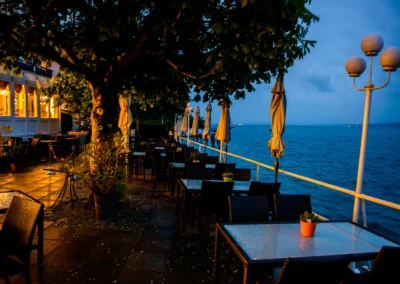 Abendliche Terrasse am Starnberger See mit gedeckten Tischen, bereit fuer eine Hochzeit.
