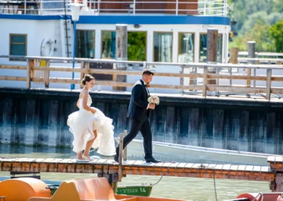 Brautpaar auf Steg bei Hochzeit im Seehaus Schreyegg, Stegen am Ammersee, Hochzeitsszene abends am Wasser.