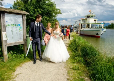 Brautpaar am Chiemsee: Hochzeit im Hotel Aiterbach mit Gaesten am Seeufer. Festliches Hochzeitsfoto im Freien.