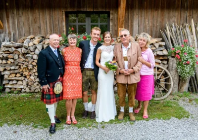 Hochzeitsgesellschaft beim Hasenoehrlhof in Geitau, festliche Tracht und Blumen, freudige Hochzeitsfeier.