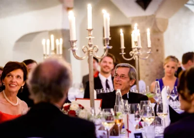 Gaste bei einer Hochzeitsfeier im Schloss Amerang, elegante Tischdekoration mit Kerzenleuchtern. Hochzeitsreportage.