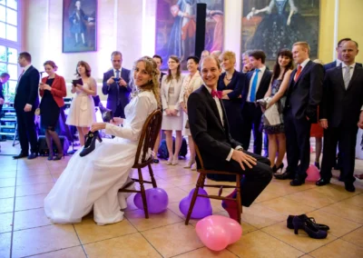 Brautpaar bei Hochzeitsspiel im Schloss Aufhausen, umgeben von Gaesten und lila Luftballons. Hochzeitsreportage.