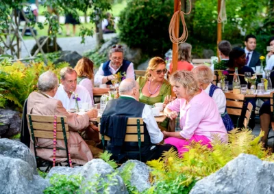 Gäste feiern im Freien eine Hochzeit im Hasenohrlhof, Geitau. Festliche Stimmung zwischen Freunden und Familie.