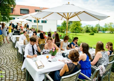 Gartenhochzeit im Hotel Aiterbach am Chiemsee mit Gaesten unter Sonnenschirmen. Romantische Hochzeitsreportage.