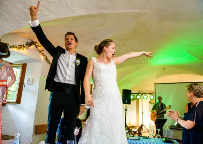 Brautpaar feiert ausgelassen auf Hochzeitsfeier im Schloss Pertenstein, Musik und Tanz sorgen für Stimmung.