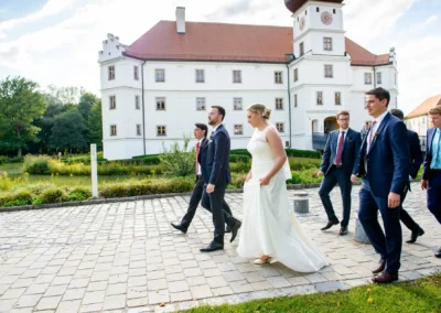 Braut wird entfuehrt und Gaeste bei Hochzeit auf Schloss Hohenkammer. Hochzeitsfotografie in stilvoller Umgebung.