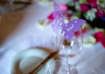 Lila Schmetterling mit Braut auf Weinglas, Tischdeko bei Hochzeit in Schloss Aufhausen. Hochzeitsreportage.