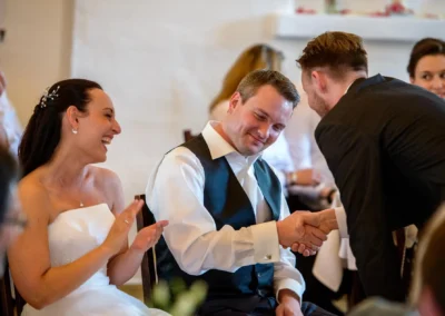 Brautpaar lacht und gratuliert Gast zur Hochzeit im Schloss Seefeld, Teil einer festlichen Hochzeitsreportage.