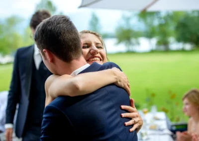 Hochzeitspaar umarmt sich gluecklich im Hotel Aiterbach am Chiemsee, mit Gruenflaeche im Hintergrund.