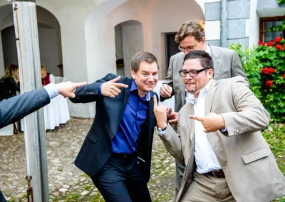 Männer in Anzügen bei Hochzeitsfeier im Schloss Pertenstein. Fröhliche Momente der Trauung im Chiemgau.