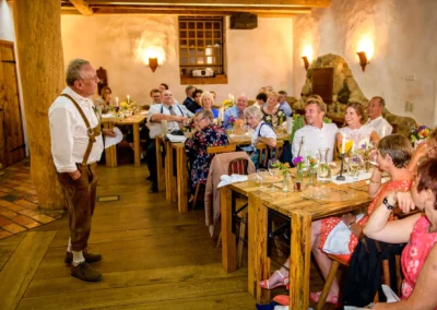 Hochzeitsfeier im Hasenoehrlhof, Geitau: Gäste geniessen eine Rede, bayrische Tradition in festlicher Atmosphäre.