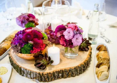 Hochzeitsdekoration mit Blumen und Kerzen auf Holzplatte. Elegante Trauung auf Schloss Hohenkammer.
