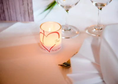 Kerze und Weinglaeser auf Hochzeitstafel im Schloss Pertenstein, Traunreut. Elegante Hochzeitsdeko im Chiemgau.