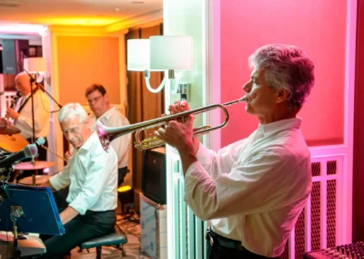 Liveband spielt bei Hochzeitsfeier im Hilton Tucherpark, Muenchen. Musiker mit Trompete und Klavier in festlicher Atmosphaere.