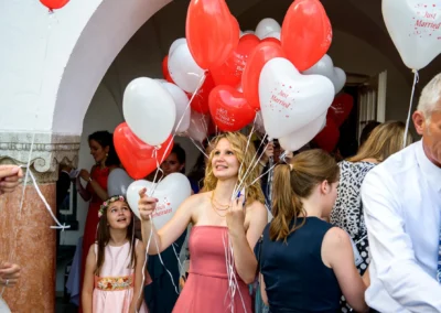 Gaste bei Hochzeit im Hotel Aiterbach am Chiemsee mit roten und weissen Luftballons in Herzform.