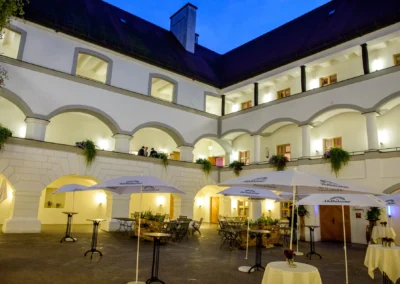 Schloss Hohenkammer Innenhof bei Nacht, beleuchtet, Hochzeitslocation, Tische und Sonnenschirme, Hochzeitsreportage.