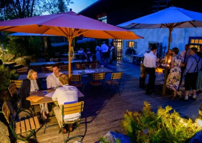 Outdoor Hochzeitsfeier im Hasenoehrlhof, Geitau mit Gaesten bei Abenddaemmerung. Elegante Atmosphaere in Bayrischzell.