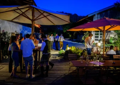 Hochzeitsfeier im Freien bei Nacht im Hasenoehrlhof, Gaeste unter Sonnenschirmen, Geitau bei Bayrischzell.