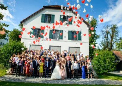 Hochzeitsgesellschaft mit Ballons im Hotel Aiterbach am Chiemsee bei sonnigem Wetter. Festliche Stimmung.
