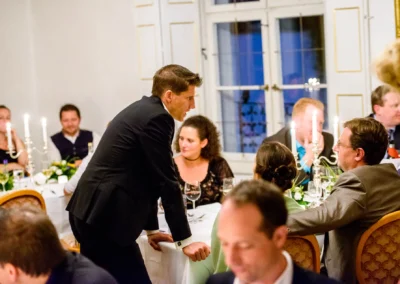 Hochzeitsfeier im Schloss Pertenstein, Gaeste unterhalten sich am festlich gedeckten Tisch, Hochzeitsreportage.