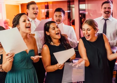 Fröhliche Hochzeitsfeier im Hilton Tucherpark, München. Gäste singen und feiern bei der Trauung. Hochzeitsreportage.