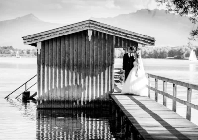 Brautpaar am Chiemsee Steg bei Hotel Aiterbach. Hochzeitsfotografie in malerischer Kulisse.