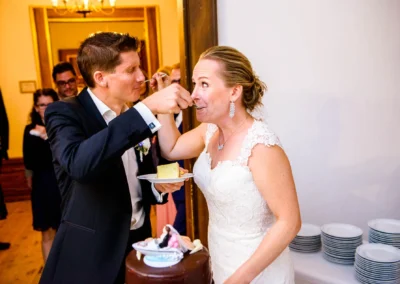 Hochzeit im Schloss Pertenstein: Brautpaar teilt Torte. Eleganter Moment der Trauung im Chiemgau festgehalten.